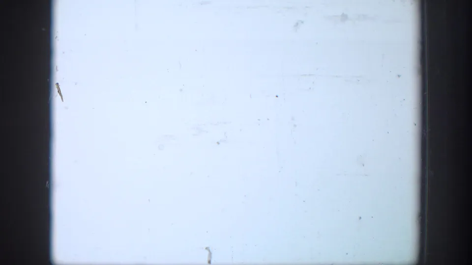 Overexposed 8mm frame from the clip, showing a washed-out field with small dust marks and dark film borders.