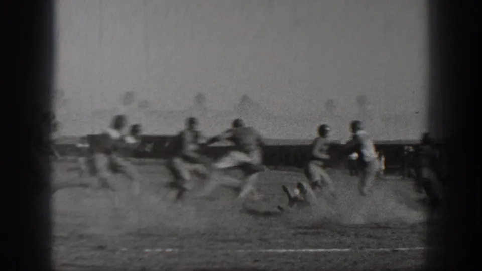 A blurred 8mm frame shows a football runner pursued by several players on a dusty field in the 1938 Washington clip.