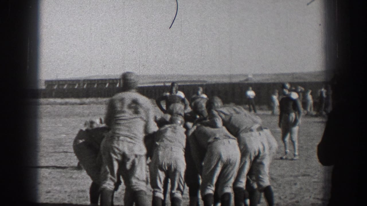 1938 Washington home-movie frame showing helmeted football players clustered at the line on an outdoor grass field.