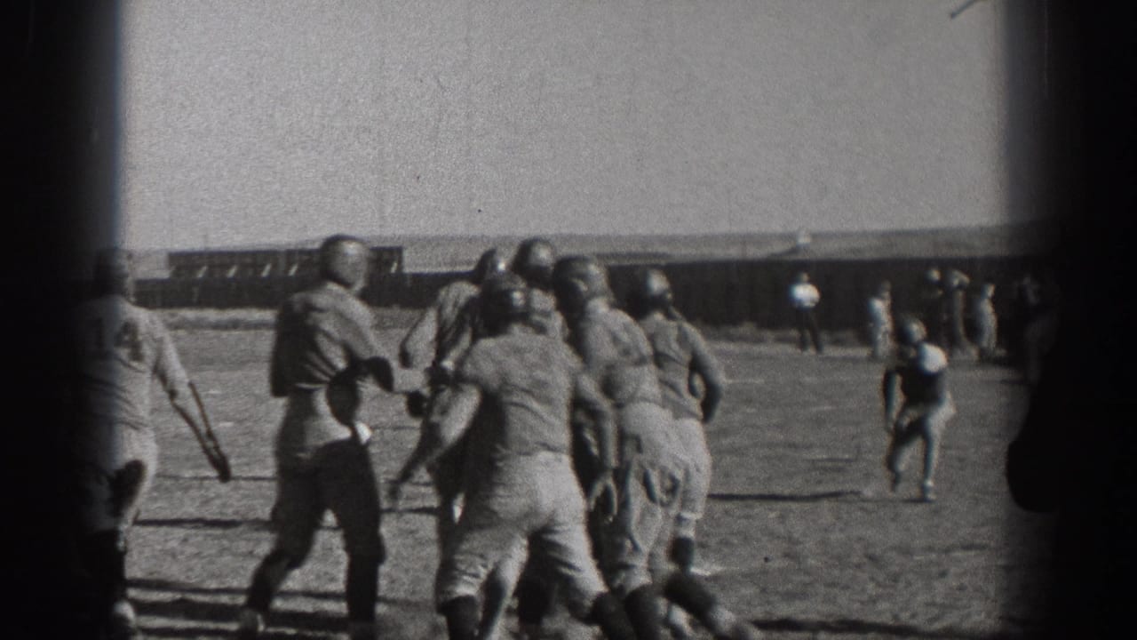 Helmeted football players collide as a play develops on the field.