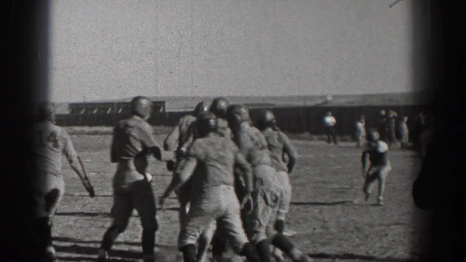 1938 Washington footage shows football players in period uniforms blocking and moving across a grass field.