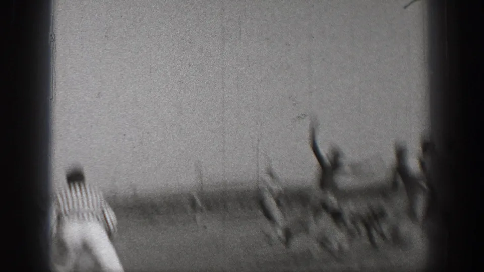 1938 Washington home-movie frame showing blurred football players in motion on an open field as a striped referee watches from the side.