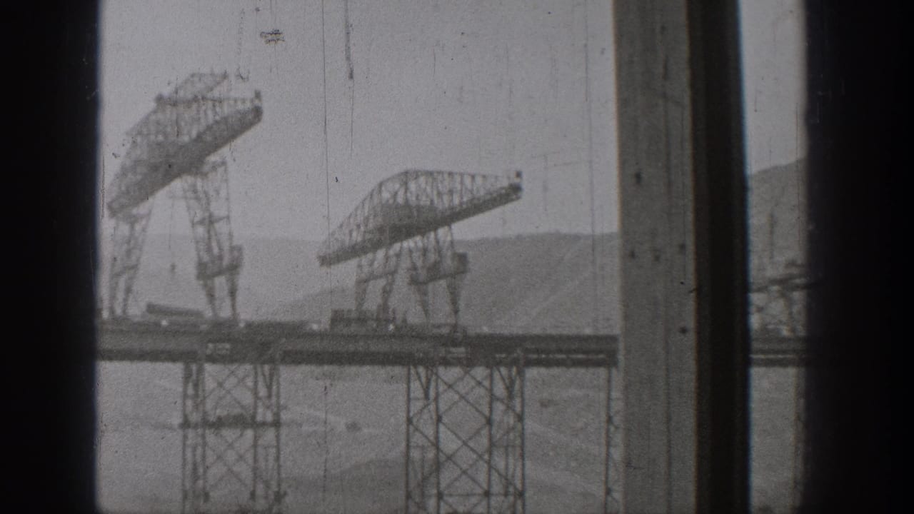 1938 Washington home-movie view of elevated trusswork and support towers across water, framed by dark interior window divisions.