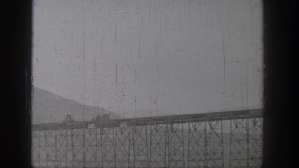 A train appears to cross a long steel bridge in Washington, 1938, filmed from a distant home-movie viewpoint.