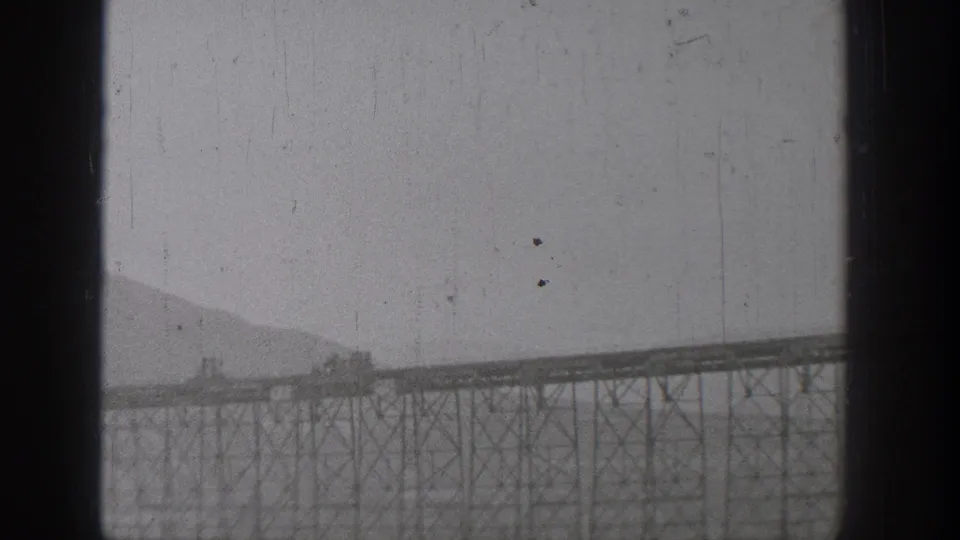 Home-movie view of the bridge and surrounding Washington river landscape, with heavy film edges and soft 8mm texture.