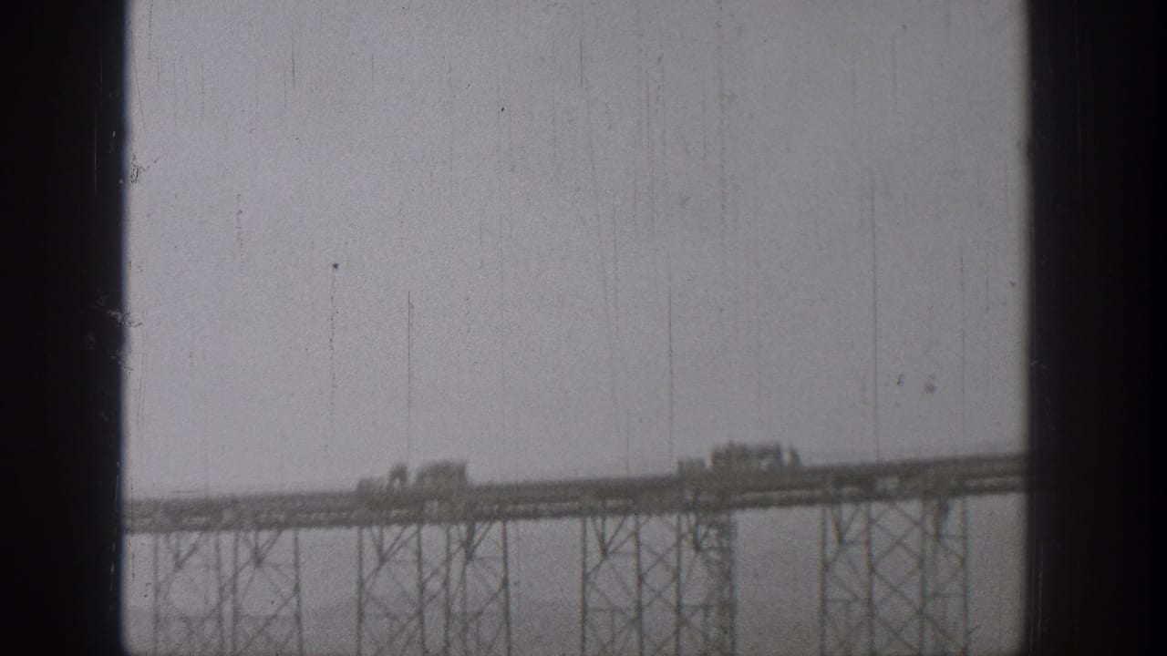 Several vehicles move along the bridge deck above a line of steel supports.