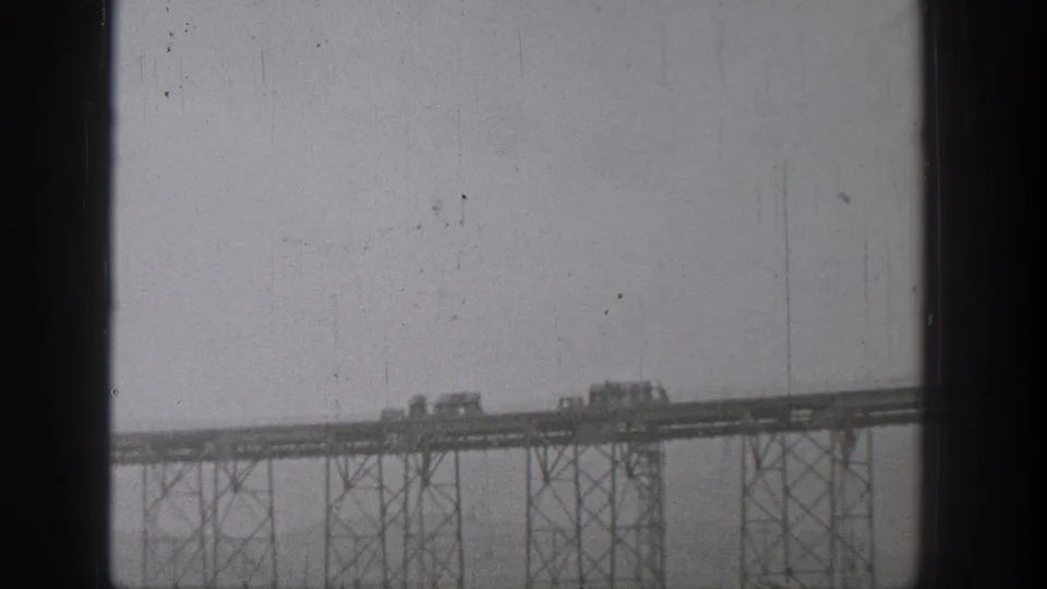 Grainy 1938 Washington frame showing vehicles clustered on an elevated bridge deck above steel trestles.