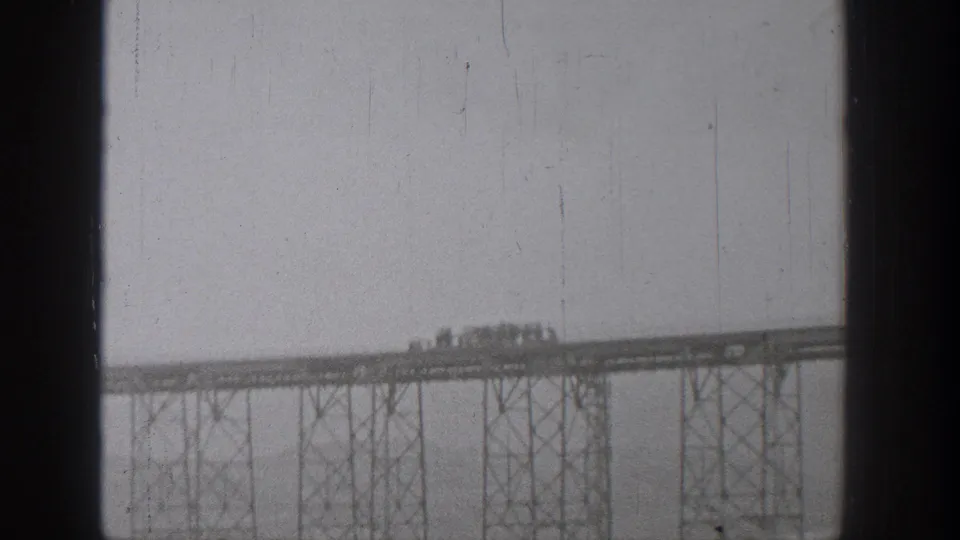 Final 1938 Washington bridge frame showing distant trucks or cars on an elevated steel span in grainy 8mm footage.