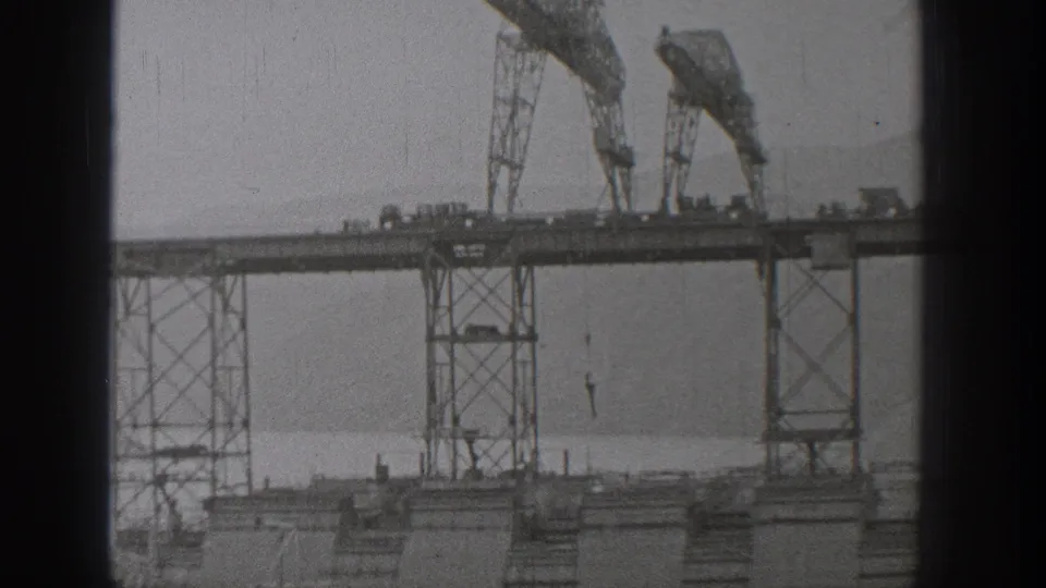 Final 1938 Washington frame with gantry machinery, a long platform, and suspended hooks in grainy 8mm footage.