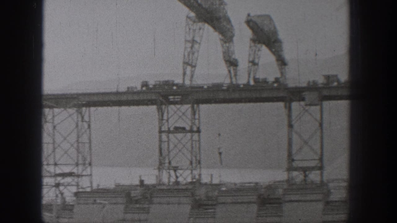 1938 Washington 8mm frame showing a bridge span under construction with cranes, steel supports, and haze beyond.