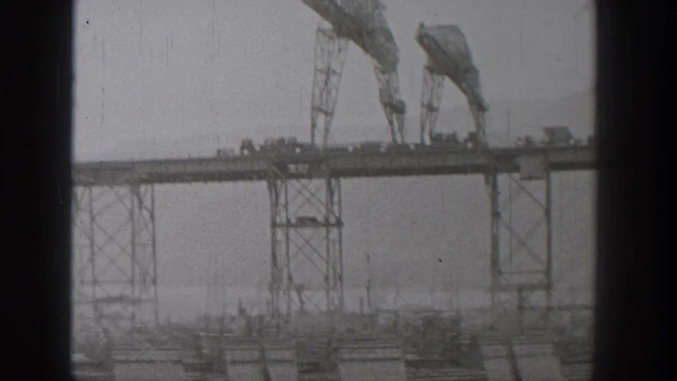 Grainy 1938 Washington 8mm view of cranes and steel supports on an unfinished bridge structure.