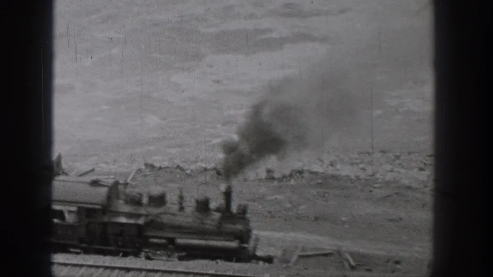 Steam locomotive on a riverside rail line in Washington, 1938, with black smoke rising against the water behind it.