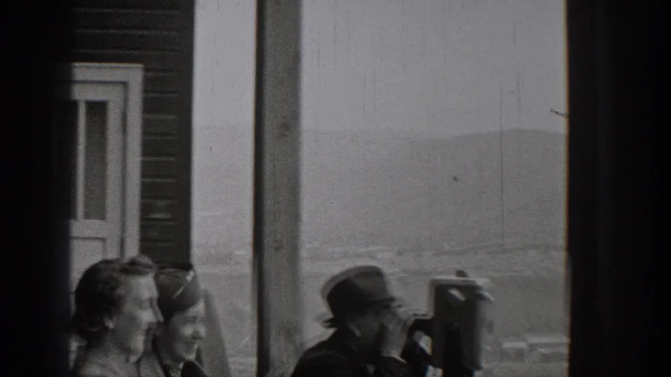 1938 Washington overlook scene with adult visitors beside a columned building and a mounted binocular viewer facing the landscape.