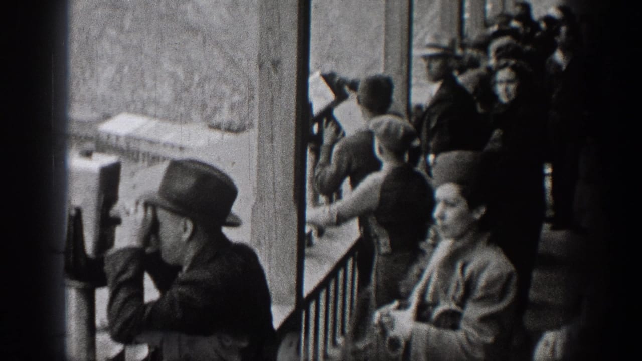 Visitors gather along a railing while a man uses a viewing scope.