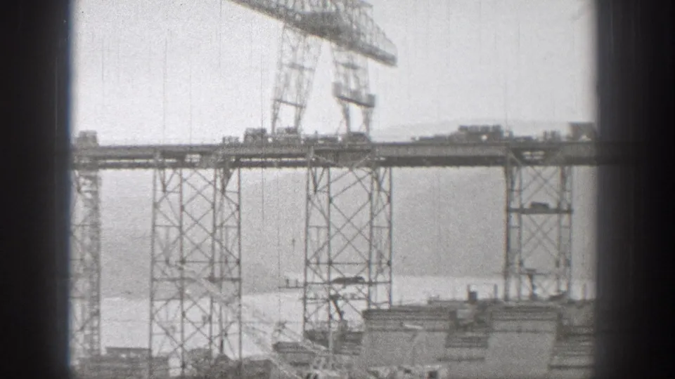 Washington bridge construction frame showing steel towers, deck work, and a gantry crane in 1938 home-movie footage.