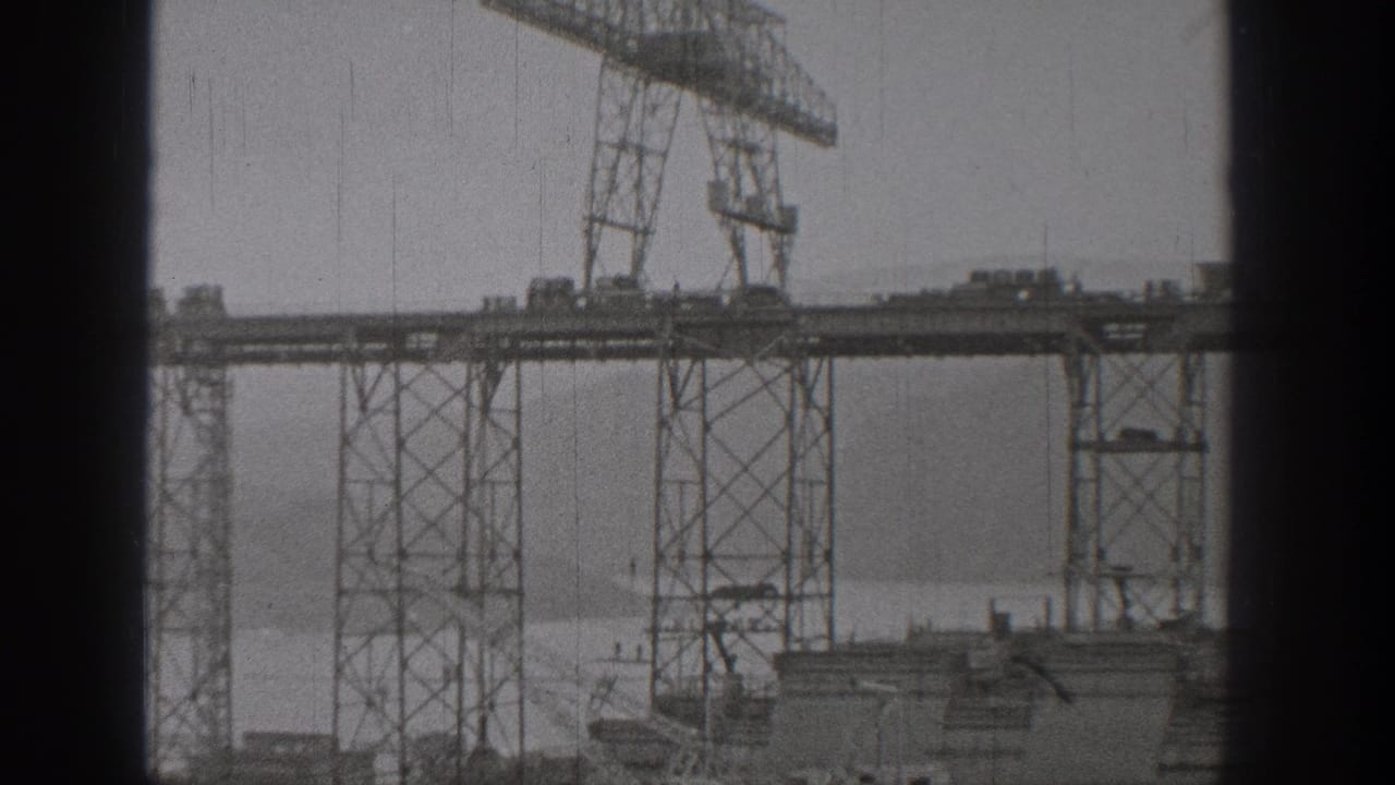 1938 Washington 8mm frame showing tall steel cranes and elevated bridge construction over a broad river.
