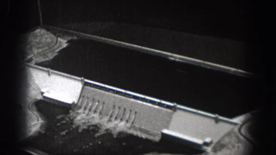 1938 Washington 8mm frame showing an aerial view over a dam structure, spillway water, and heavy black film gate edges.