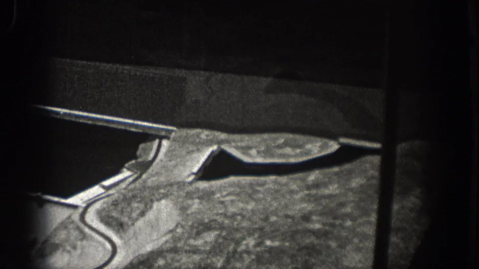 1938 Washington 8mm frame with an oblique aerial view of dam infrastructure, reservoir water, and adjacent terrain.