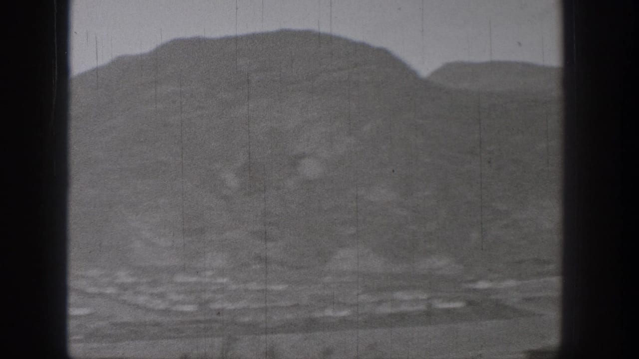 1938 Washington 8mm view of a broad mountain valley with faint water and settlement details below.