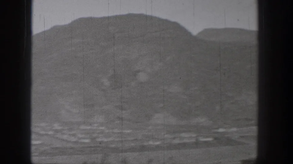 1938 Washington 8mm view of a broad mountain valley with faint water and settlement details below.