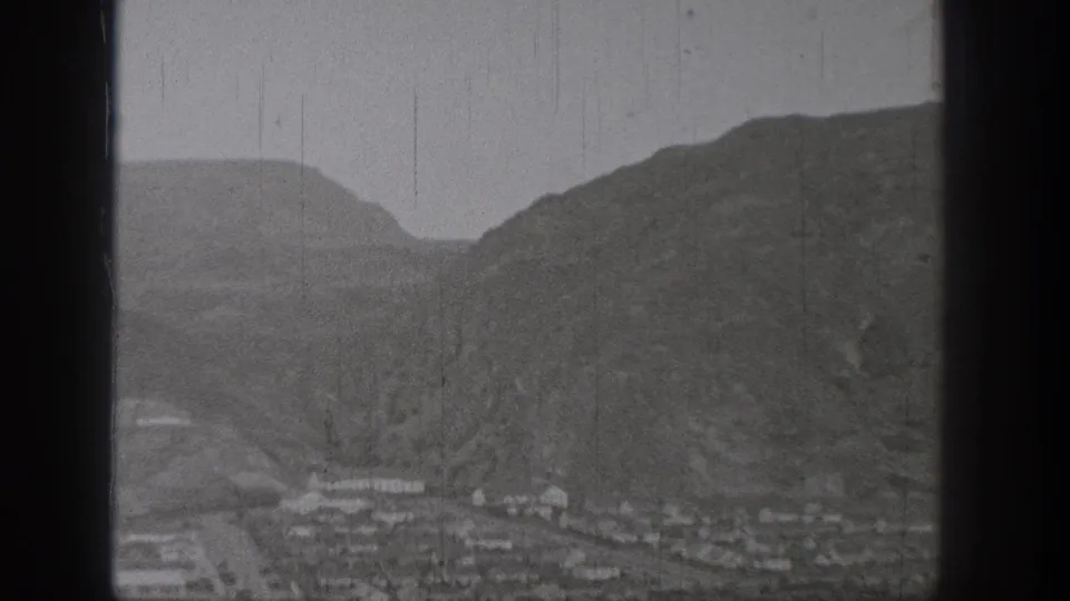 1938 Washington home-movie frame showing a valley town beneath steep mountain slopes.