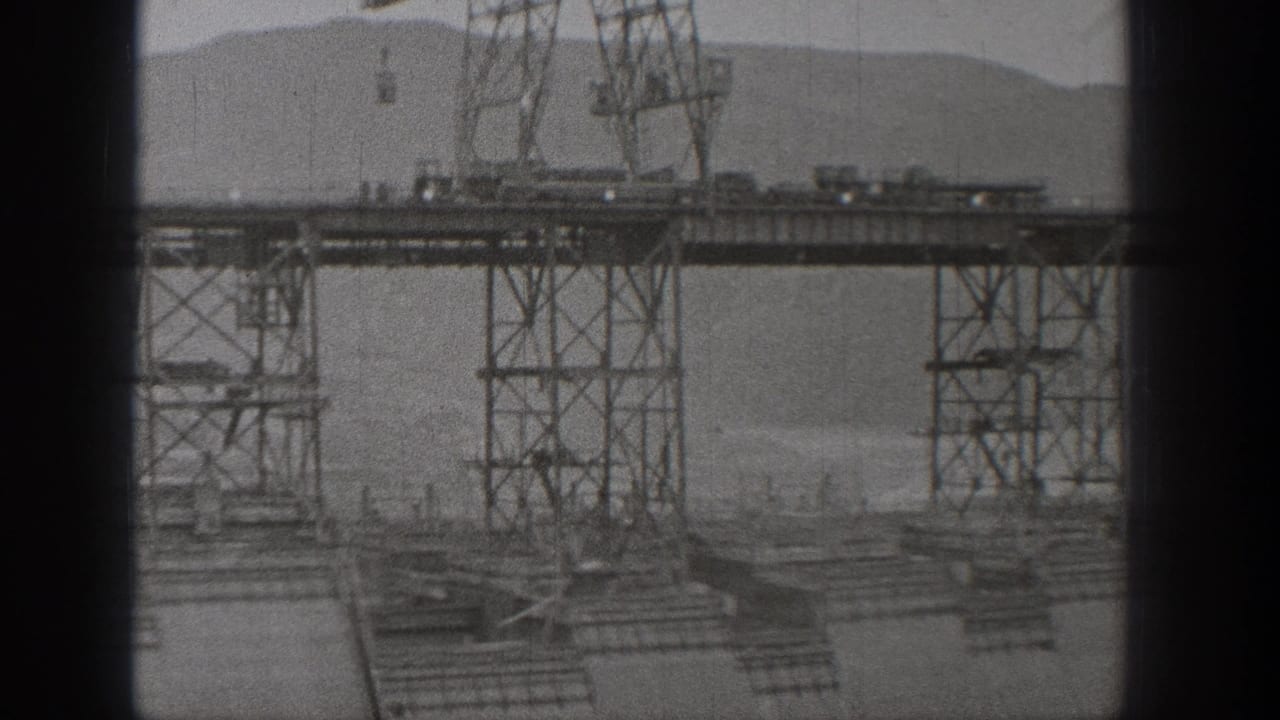 Washington dam construction scene with elevated steel supports, work decking, and hills beyond the site.