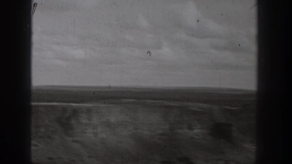Washington landscape view following the dam shots, showing open ground, low horizon, pale sky, and visible 8mm film wear.