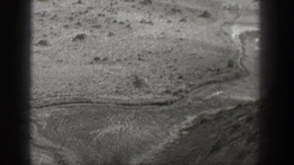 Black-and-white 1938 Washington frame showing a curved dirt path cutting through rocky, sparsely vegetated desert ground.