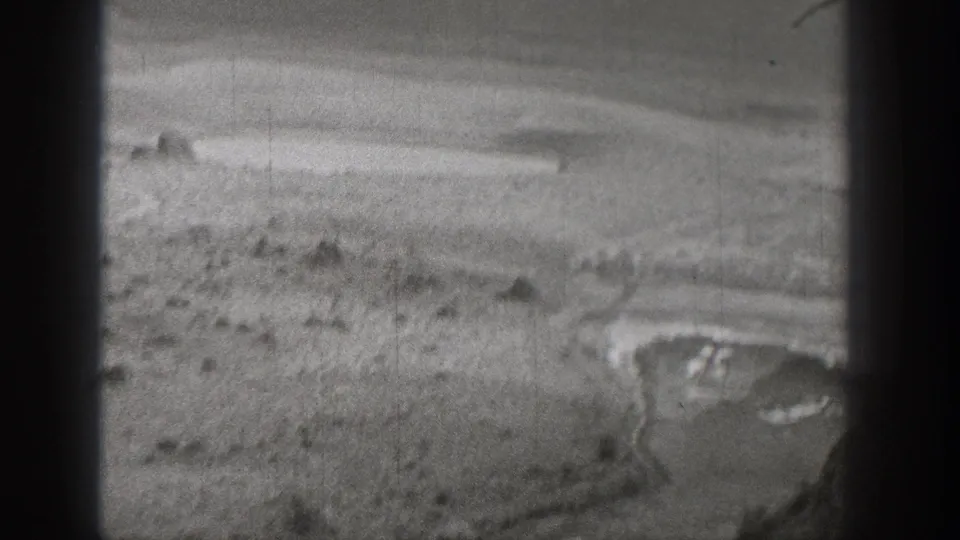 1938 Washington home-movie frame showing an arid landscape with pale ground, low hills, and a curved pool or shoreline.