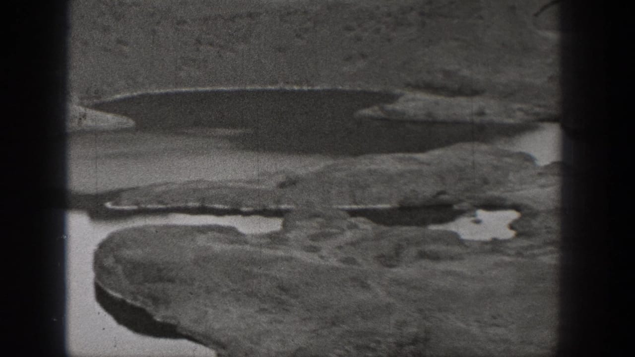 Black-and-white 1938 Washington frame showing rugged rocky ground and scattered pools in an arid landscape.