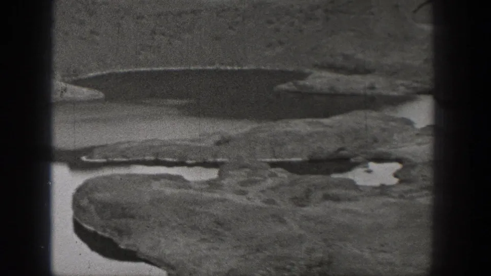 Black-and-white 1938 Washington frame showing rugged rocky ground and scattered pools in an arid landscape.