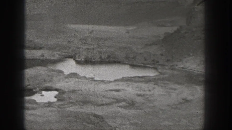 1938 Washington home-movie view of uneven dry terrain with shallow pools and distant open ground.