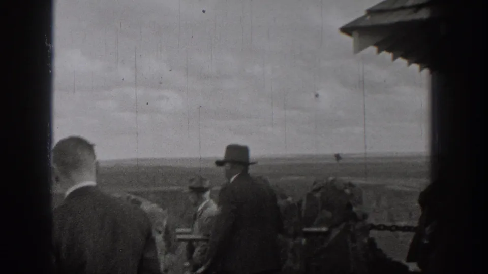 1938 Washington home-movie frame showing adults in period attire gathered near a railing while looking over open landscape.