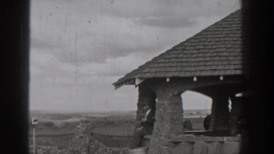 Washington 1938 home-movie frame showing a stone shelter or pagoda-like overlook structure under a cloudy sky.