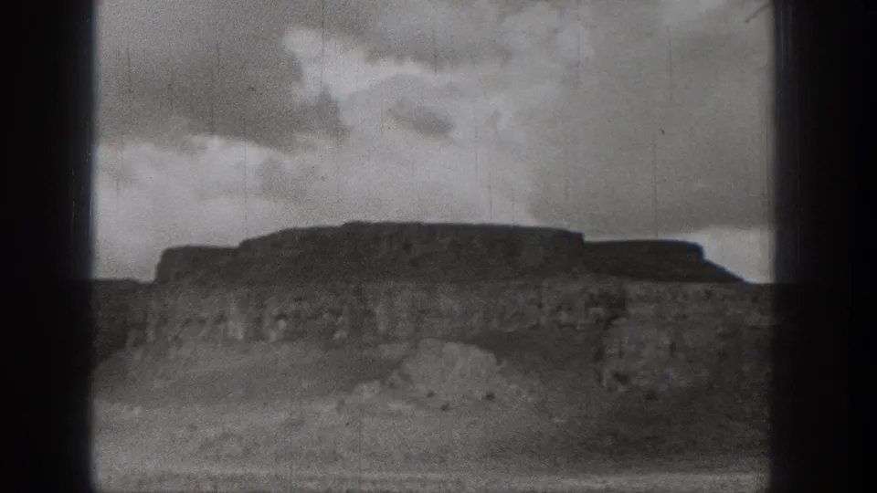 1938 Washington 8mm view of a rugged bluff or shoreline slope under a cloudy sky.