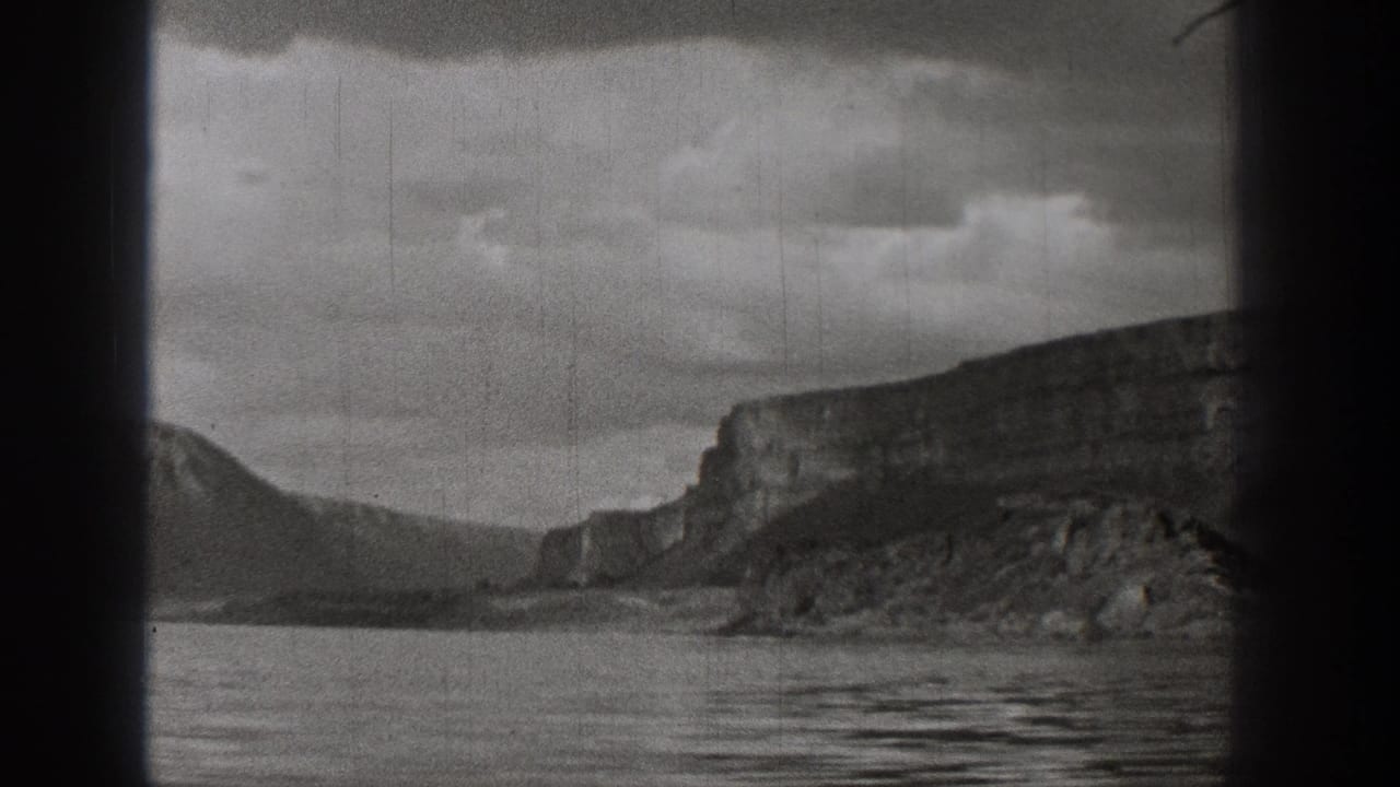 Black-and-white 1938 Washington home-movie view of lake water, distant cliffs, mountain slopes, and cloudy sky.