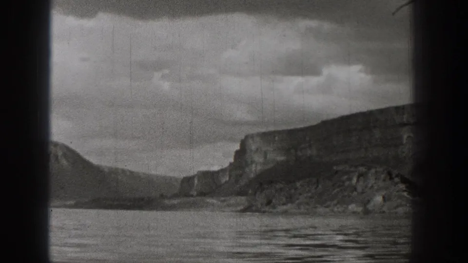 Black-and-white 1938 Washington home-movie view of lake water, distant cliffs, mountain slopes, and cloudy sky.