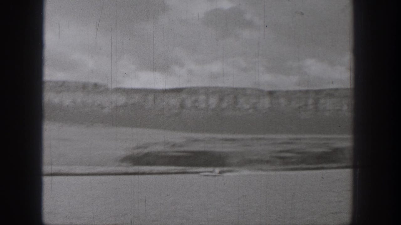 Lake and distant hillside with a small boat near the waterline under overcast clouds.