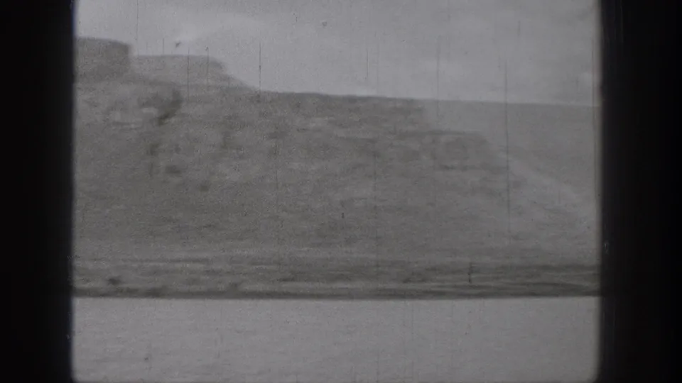 1938 Washington 8mm frame showing a broad waterway below rugged bluffs, with dark gate edges and visible film wear.