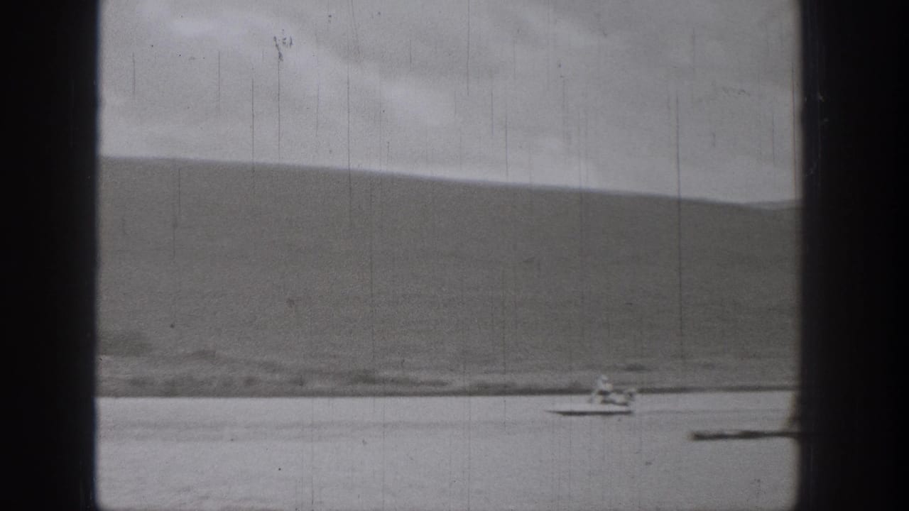 1938 Washington 8mm frame showing a small boat speeding across water with distant hills and heavy film gate edges.