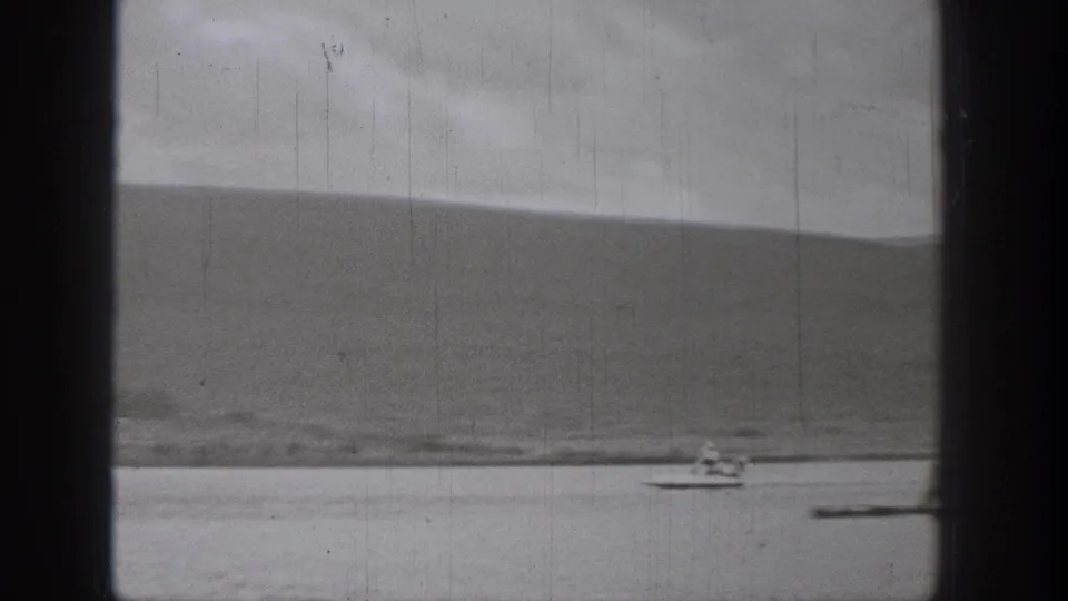 1938 Washington 8mm frame showing a small boat speeding across water with distant hills and heavy film gate edges.