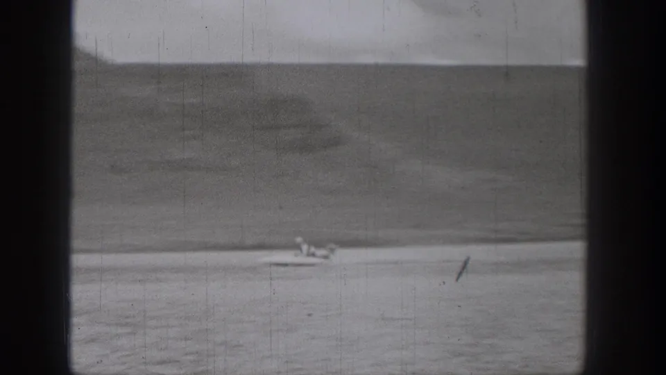 Small fast-moving boat appears far across the water in this 1938 Washington home-movie frame.