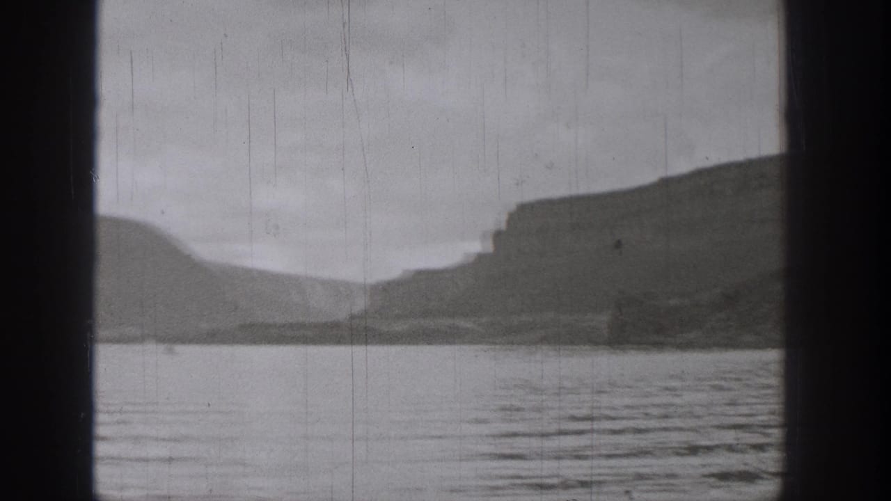 1938 Washington 8mm frame showing rippled lake water and shadowed cliff formations across the far shore.