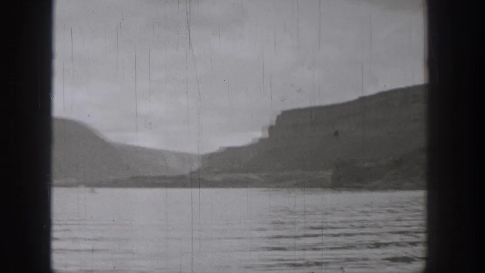 1938 Washington 8mm frame showing rippled lake water and shadowed cliff formations across the far shore.