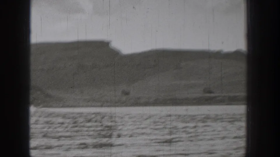 1938 Washington lake scene with low hills, distant shore, rippled foreground water, and scratched 8mm texture.