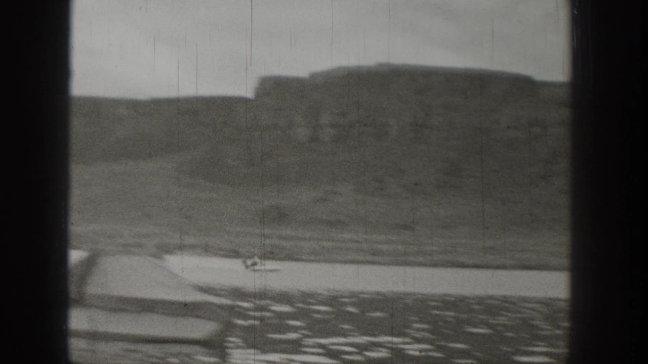 A small motorboat appears near the shoreline in 1938 Washington lake footage, with cliffs and rolling terrain in the background.