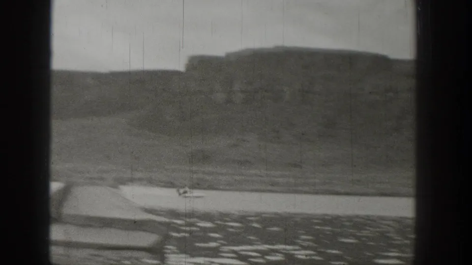 A small motorboat appears near the shoreline in 1938 Washington lake footage, with cliffs and rolling terrain in the background.