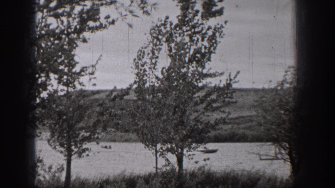 1938 Washington home-movie frame with trees in the foreground and small boats crossing a lake beyond.