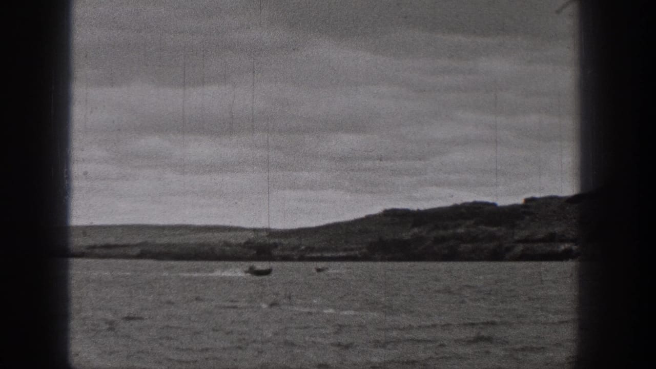 1938 Washington 8mm frame showing rippled lake water, small boats, low hills, and cloud cover.