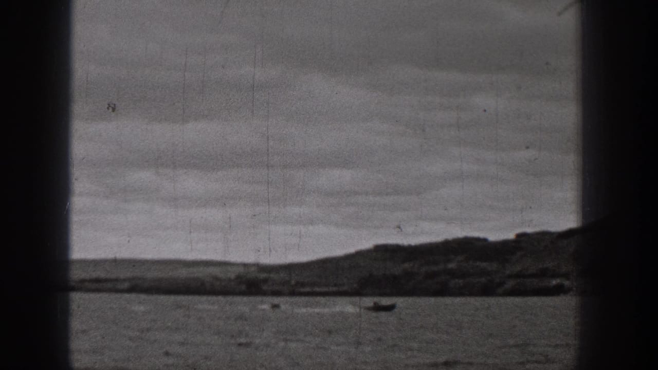 1938 Washington home-movie frame of a lake with distant small boats, low hills, and visible film wear.